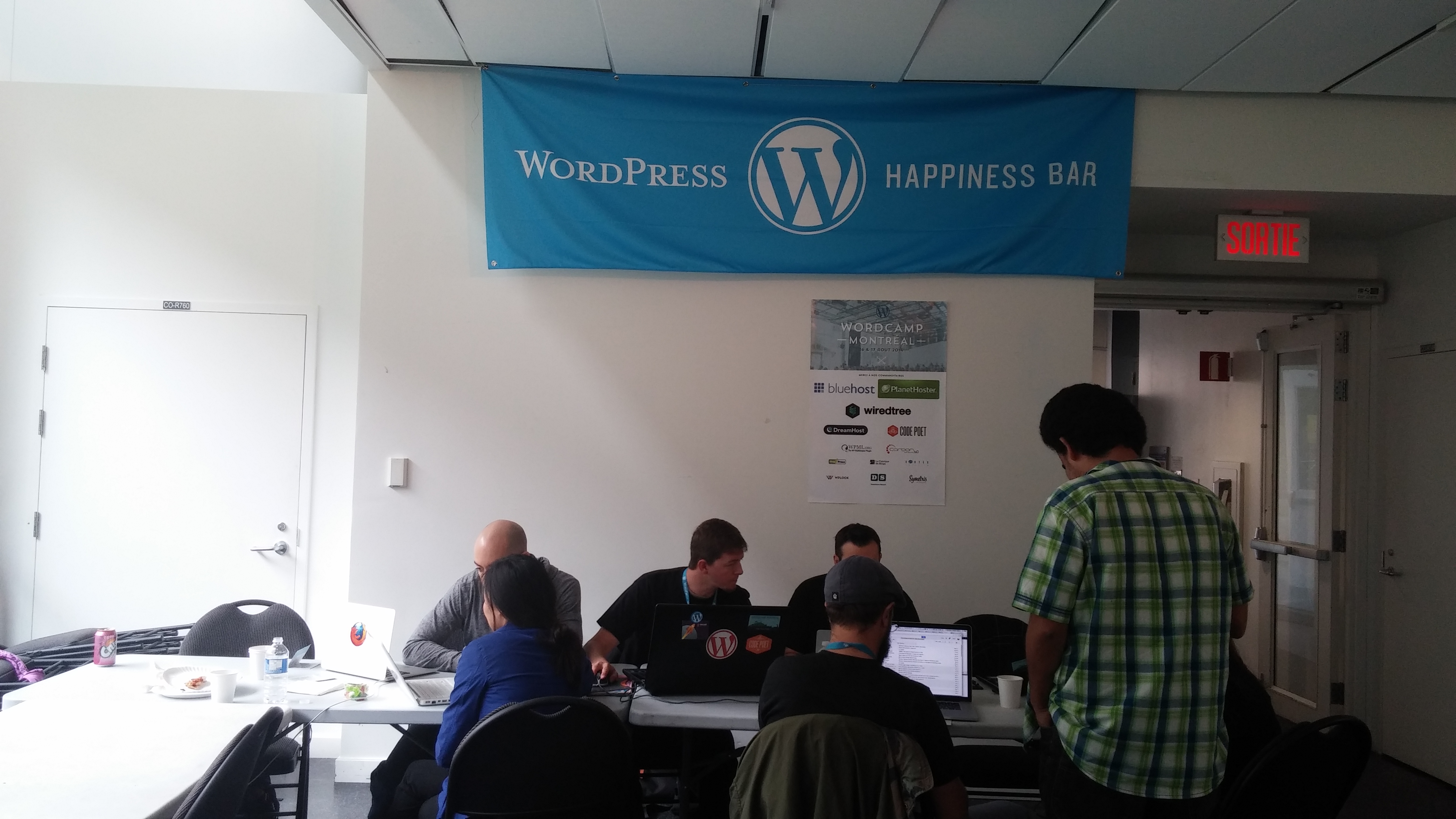 Volunteers sitting at a table with laptops assisting WordCamp attendees
