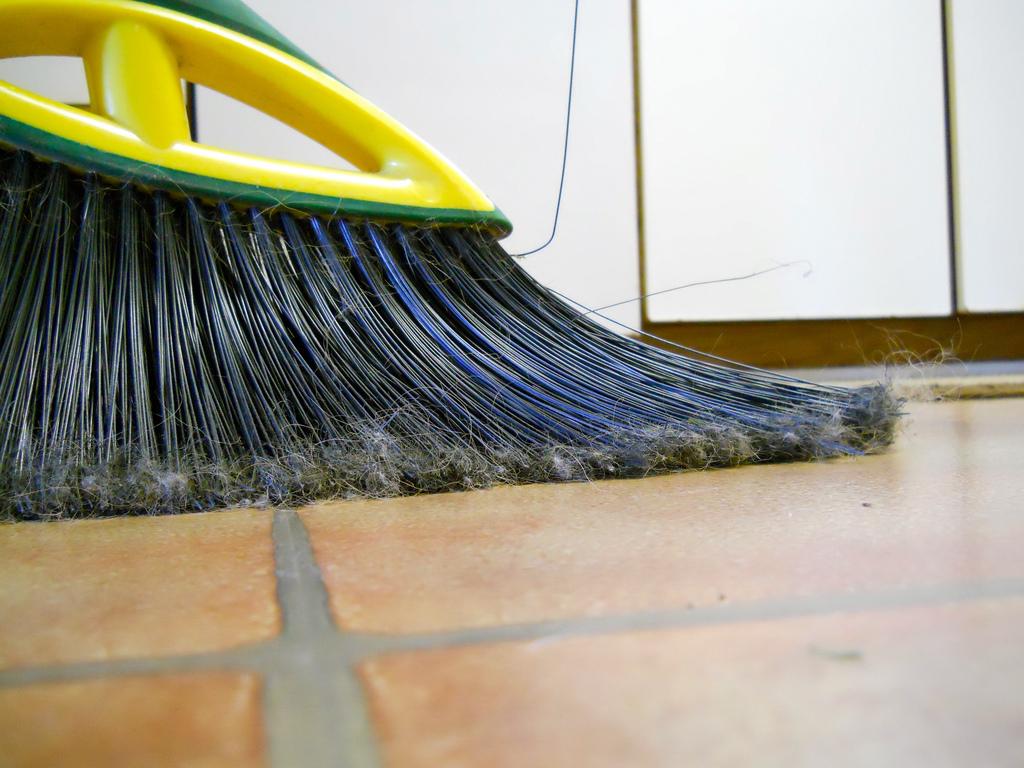 A broom sweeping a tile floor