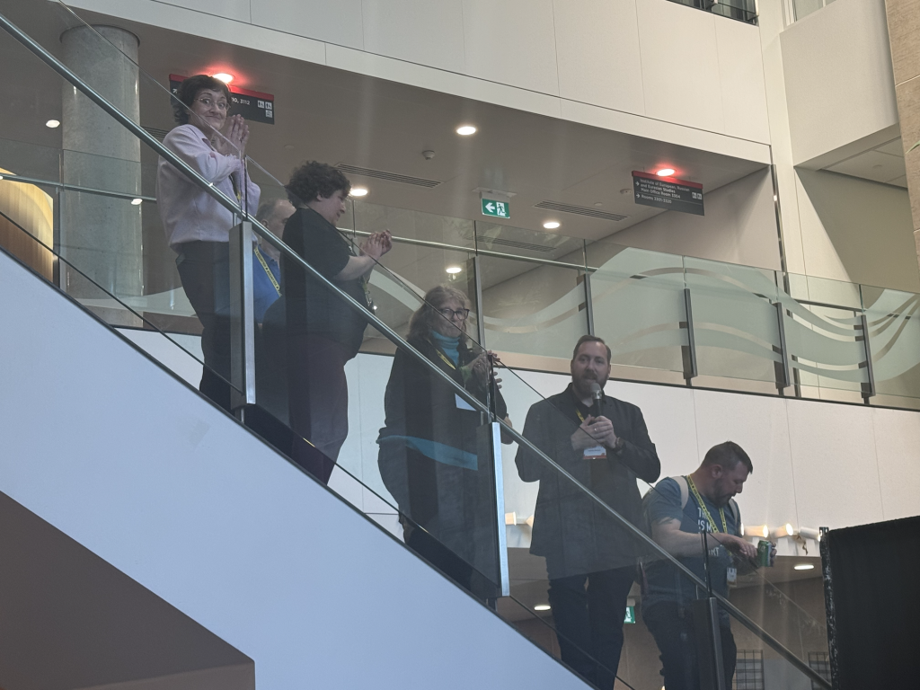 Members of the organizing team standing on a flight of stairs overlooking the audience. 