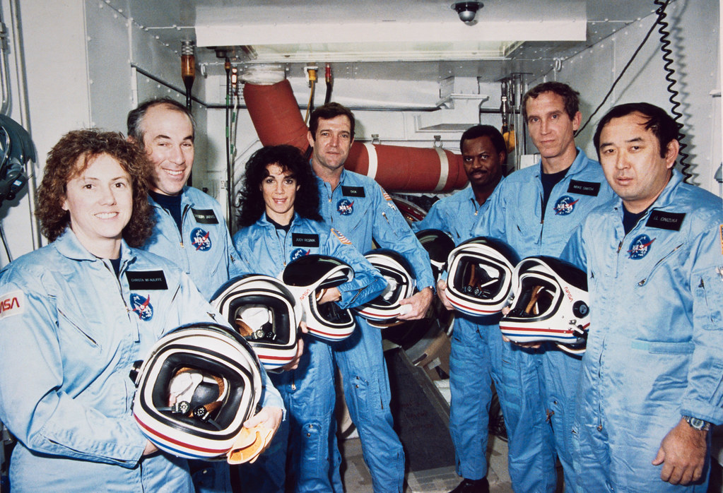 Photograph of the crew of the Challenger crew in 1986. The astronauts are holding the helmets.